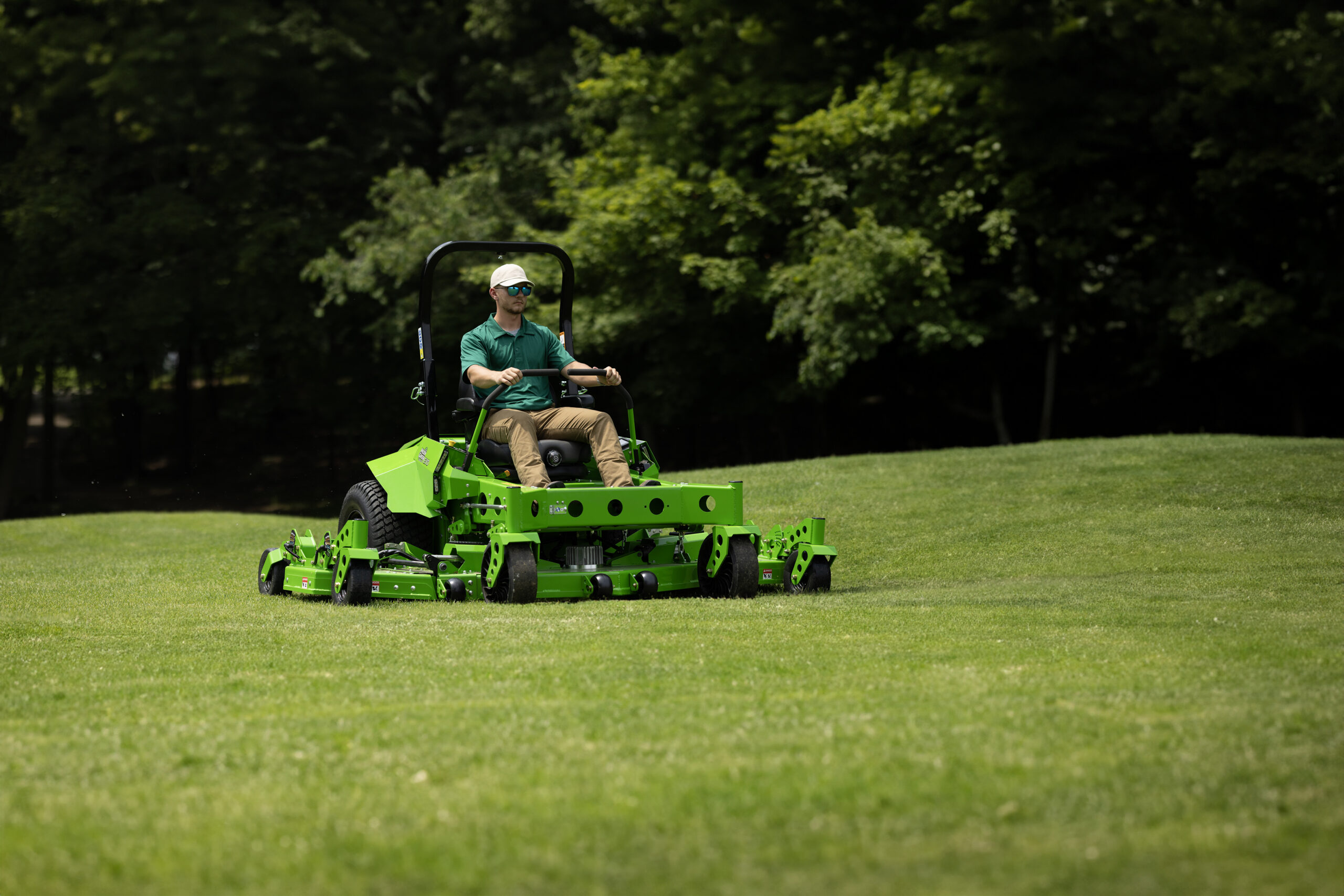 Landscaper mowing a large green property on a Mean Green all-electric mower